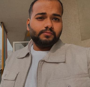 Portrait of Sushil Kumar smiling in a yellow bomber jacket on a beige background